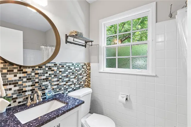 a bathroom with a granite countertop sink mirror vanity and a toilet
