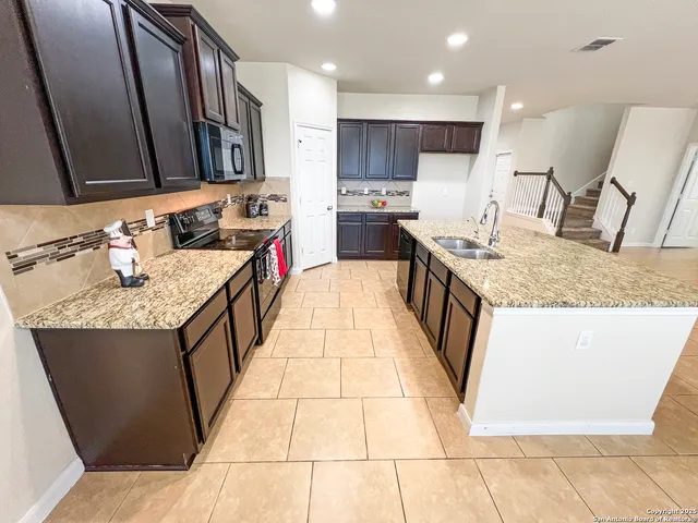 a large kitchen with kitchen island granite countertop a sink a counter top space and cabinets