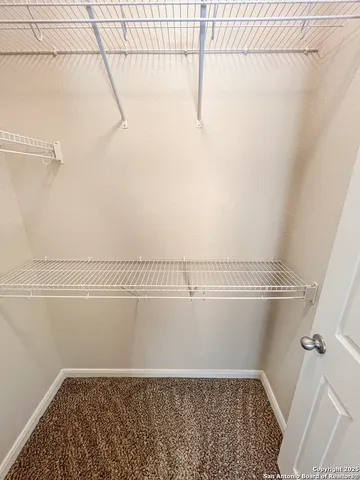 an empty room with a chandelier fan and windows