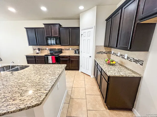 a kitchen with kitchen island granite countertop a refrigerator and a stove