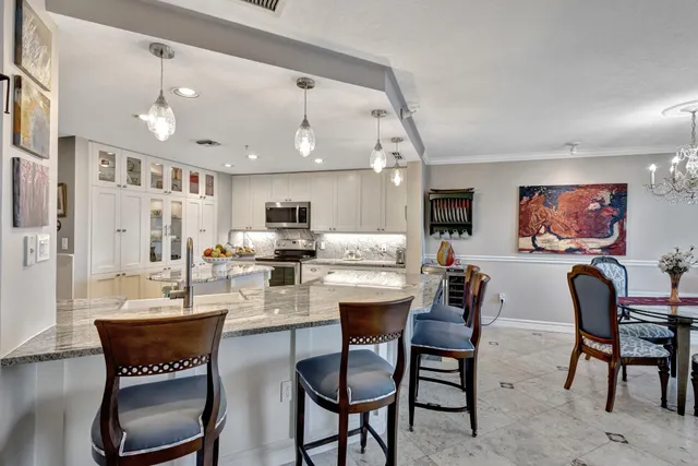 a dining room with stainless steel appliances kitchen island granite countertop a dining table chairs and a refrigerator