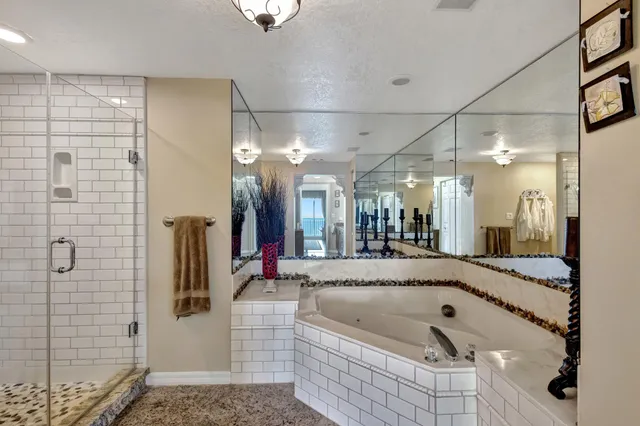 a bathroom with a tub a mirror and shower