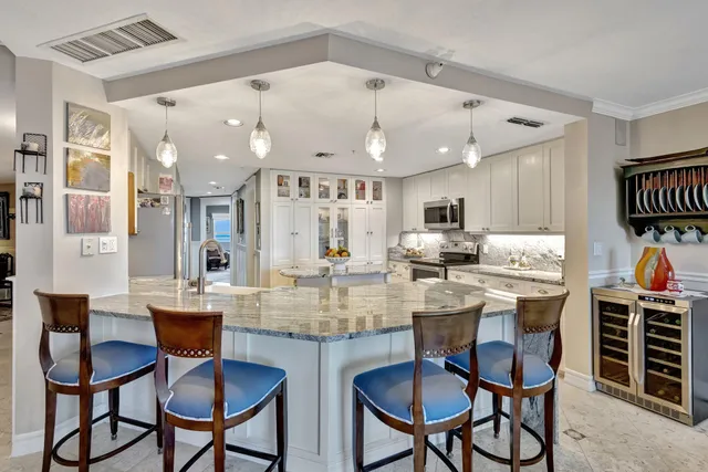 a kitchen with stainless steel appliances kitchen island granite countertop a dining table chairs and white cabinets