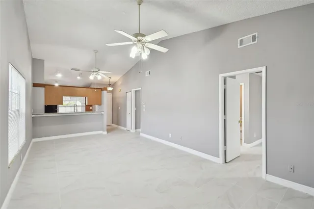 an empty room with a kitchen and a ceiling fan