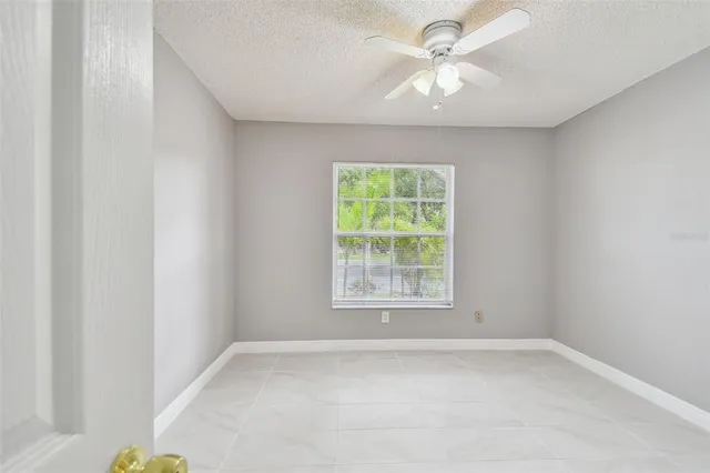 an empty room with a window and a fan