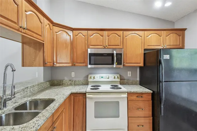 a kitchen with stainless steel appliances granite countertop a refrigerator sink and stove top oven