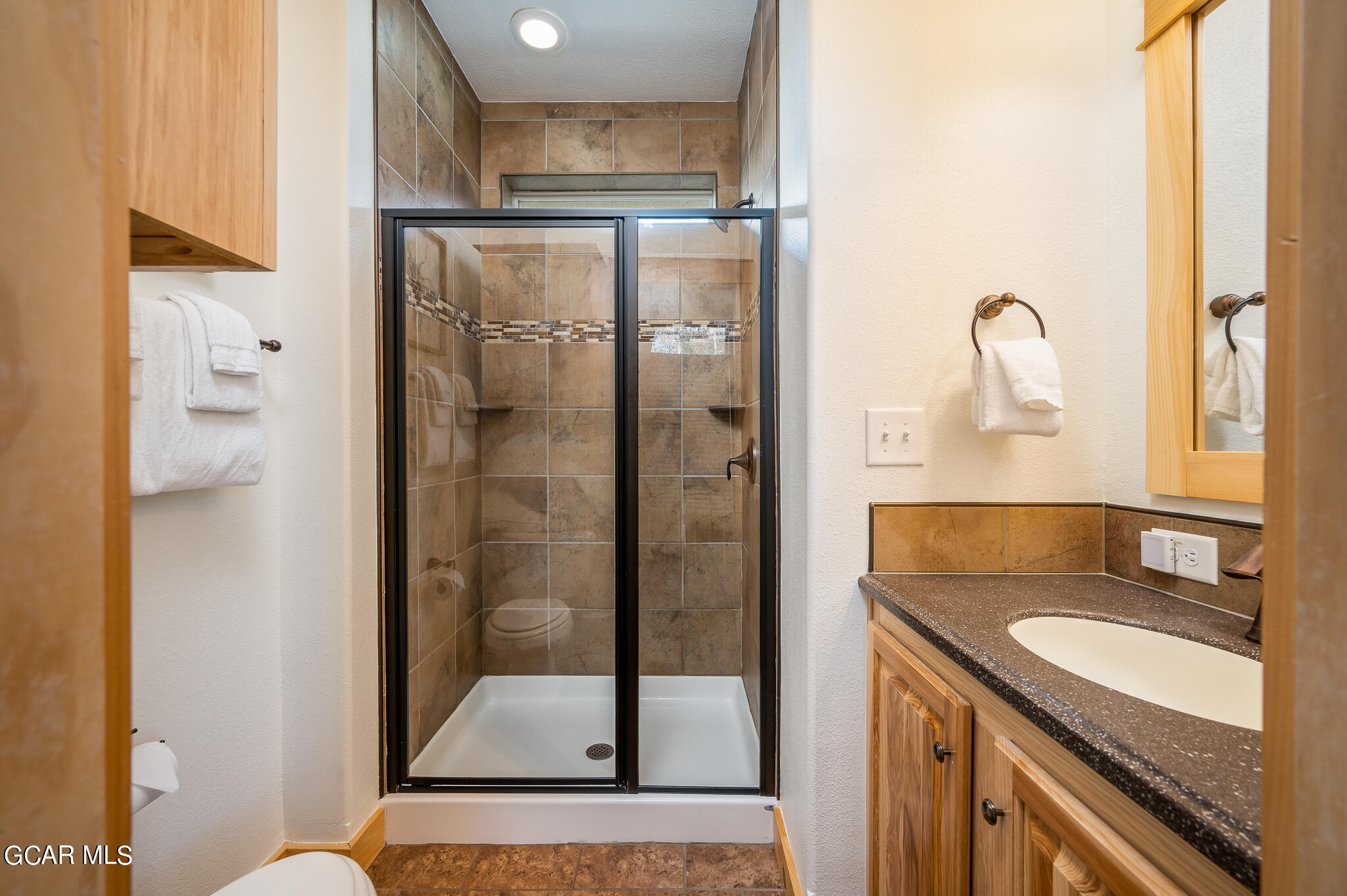 107 Edgewater Circle Granby, CO 80446 - Photo 32 of 51 a bathroom with a granite countertop shower a sink and a mirror
