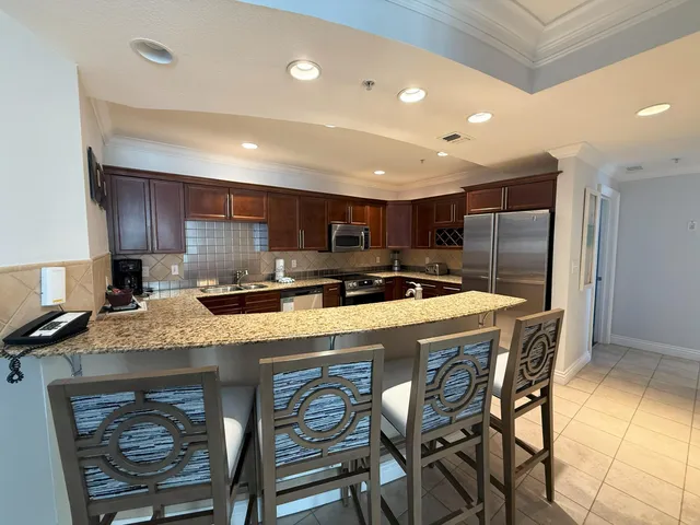 a kitchen with stainless steel appliances granite countertop a table chairs sink refrigerator and microwave