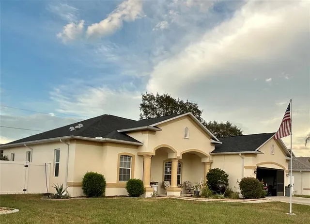 a view of a white house with a big yard and large trees