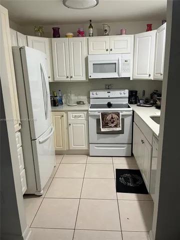 a kitchen with white cabinets a sink and white appliances