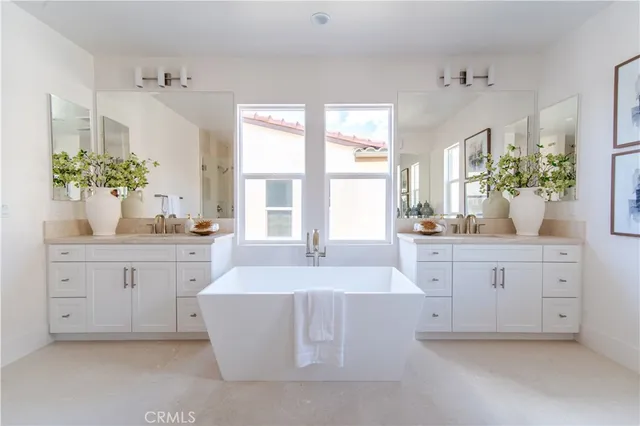 a spacious en suite bathroom with a granite countertop double vanity sink a mirror and a bathtub