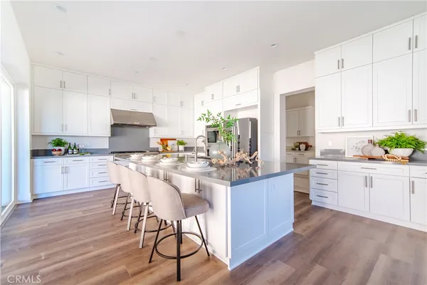 a kitchen with kitchen island granite countertop wooden floors and white stainless steel appliances