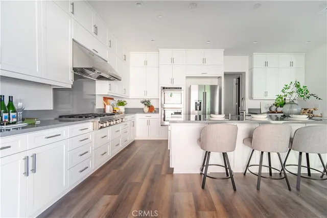 a large kitchen with cabinets wooden floor and stainless steel appliances