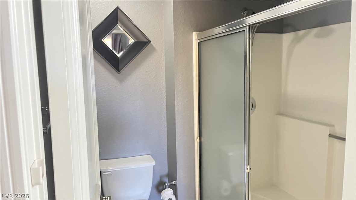 210 East Flamingo Road, Unit 205 Las Vegas, NV 89169 - Photo 16 of 17 A compact bathroom featuring a toilet and a shower with sliding frosted glass doors, maximizing functional space.