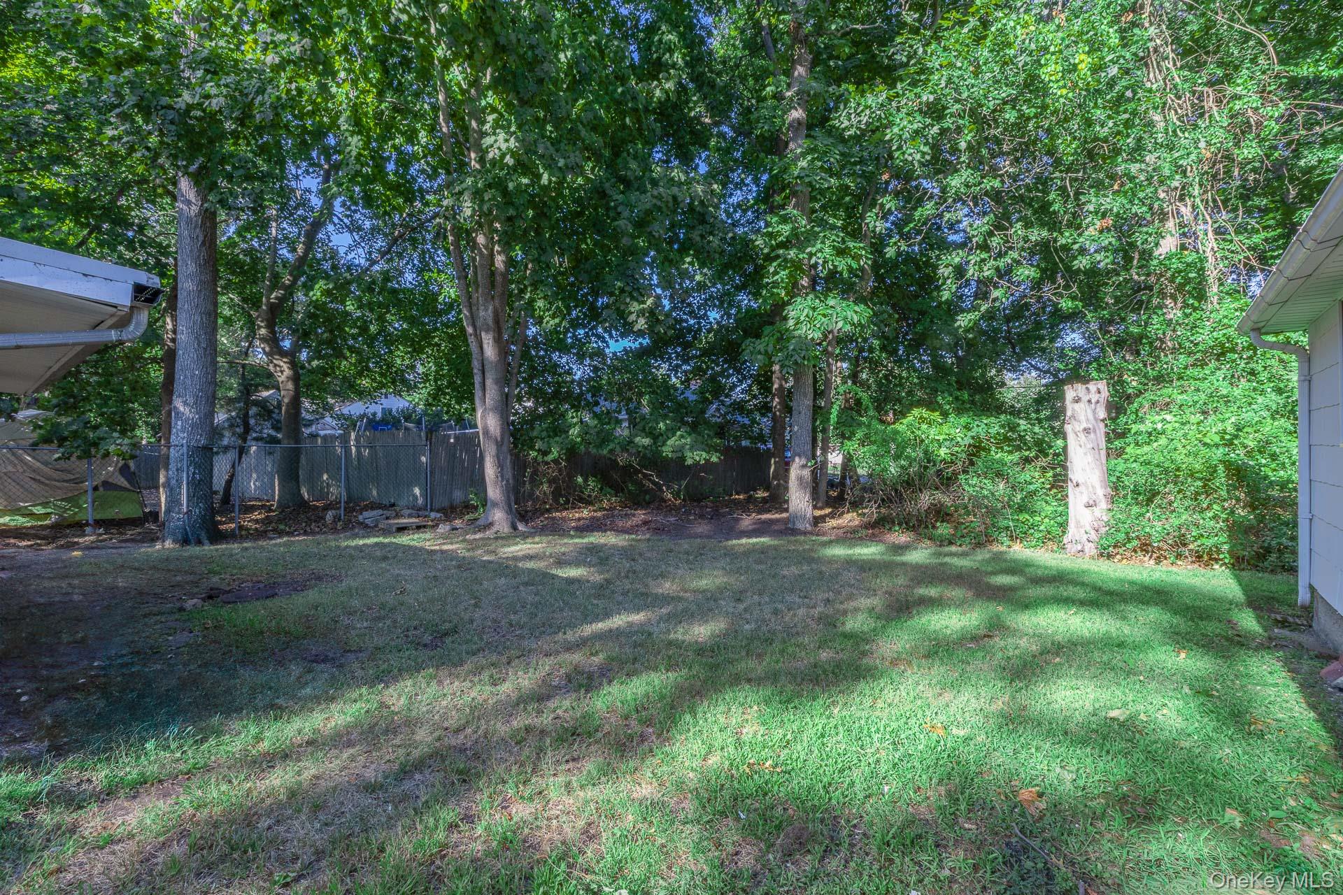 261 Elm Road West Mastic Beach, NY 11951 - Photo 22 of 22 a view of a backyard with large trees and plants