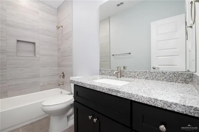 a bathroom with a granite countertop toilet a sink and a bathtub