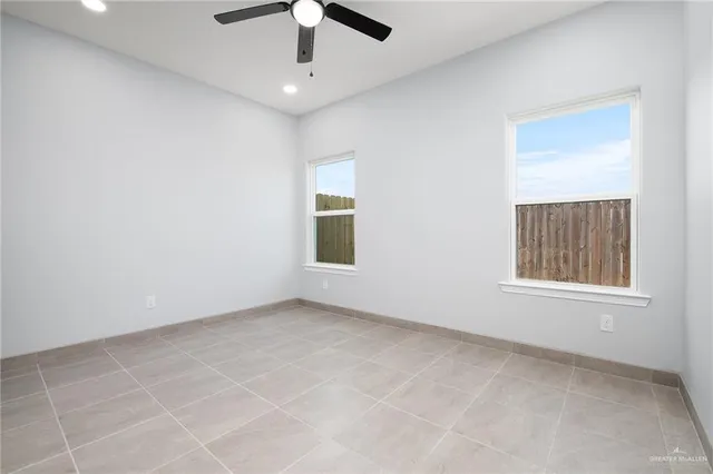 an empty room with a ceiling fan and windows