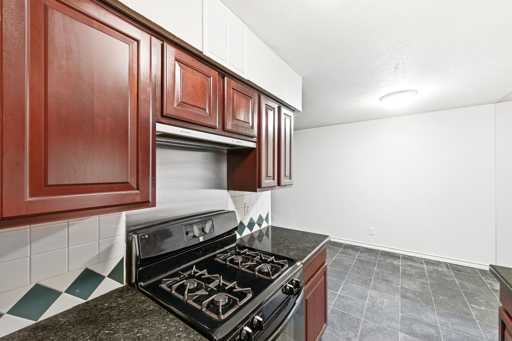 505 West 7th Street, Unit 106 Austin, TX 78701 - Photo 12 of 21 Kitchen featuring gas range oven, tasteful backsplash, dark stone countertops, and a textured ceiling