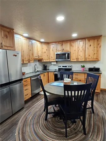 a kitchen with stainless steel appliances granite countertop a dining table chairs refrigerator and microwave