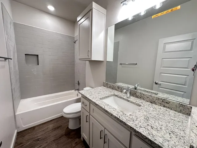 a bathroom with a granite countertop sink a toilet and bathtub