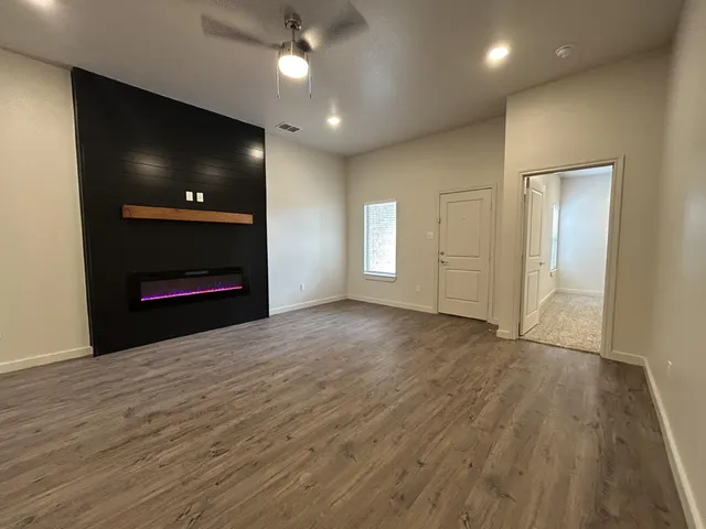 an empty room with wooden floor fireplace and fan