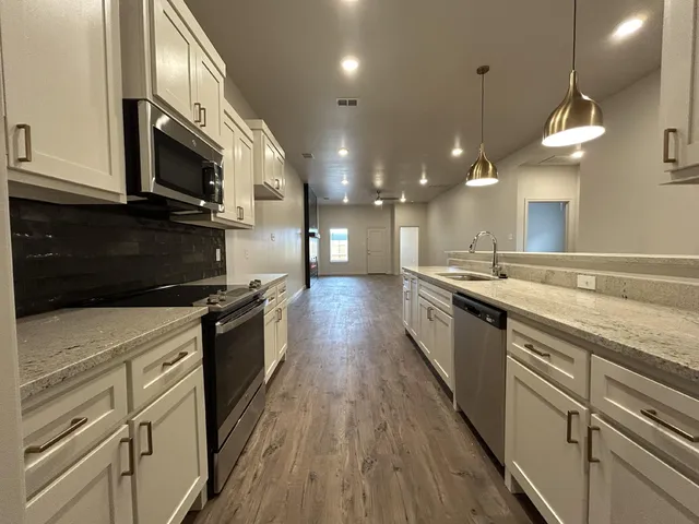 a large kitchen with stainless steel appliances kitchen island granite countertop a stove a sink and a microwave