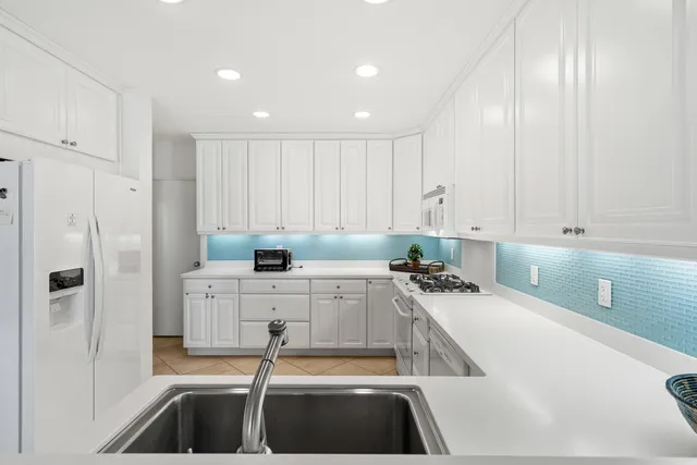 a kitchen with a sink a stove a refrigerator and white cabinets