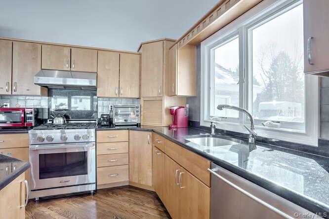 89 Spook Rock Road Suffern, NY 10901 - Photo 14 of 44 a kitchen with granite countertop a sink stainless steel appliances white cabinets and a window