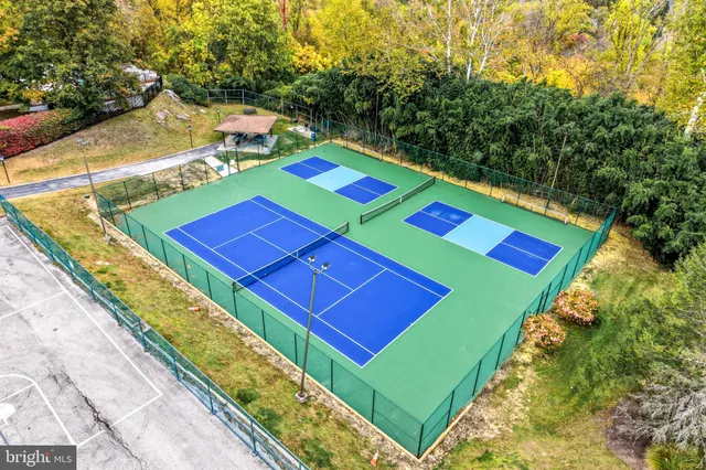 a view of a tennis ground with large trees
