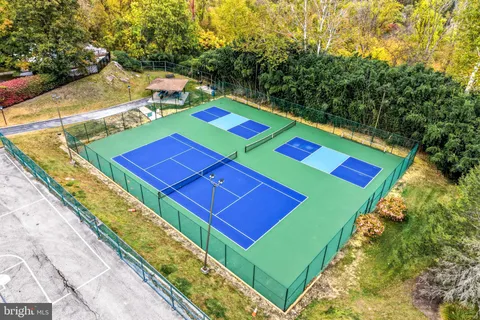 a view of a tennis ground with large trees