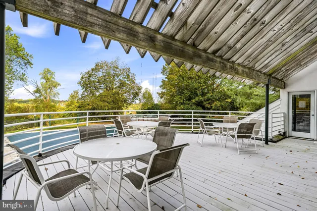 a view of a chairs and table on the wooden roof deck