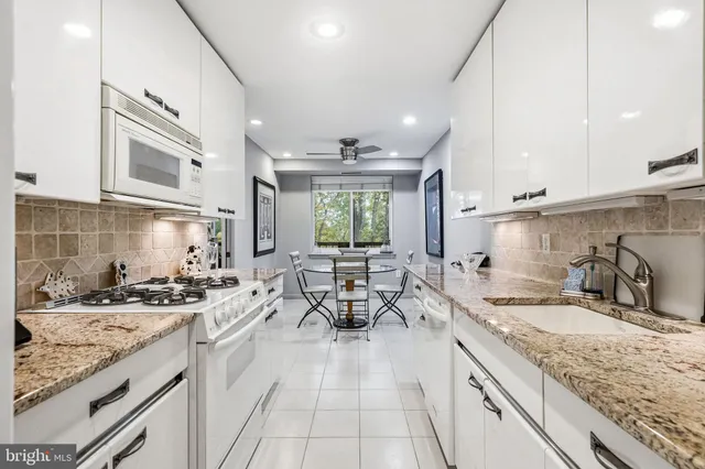 a large kitchen with granite countertop a sink and a white stove