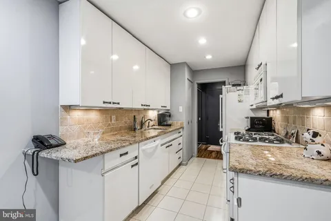 a kitchen with stainless steel appliances kitchen island granite countertop a sink refrigerator and cabinets