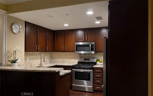 a kitchen with kitchen island granite countertop a sink cabinets and stainless steel appliances