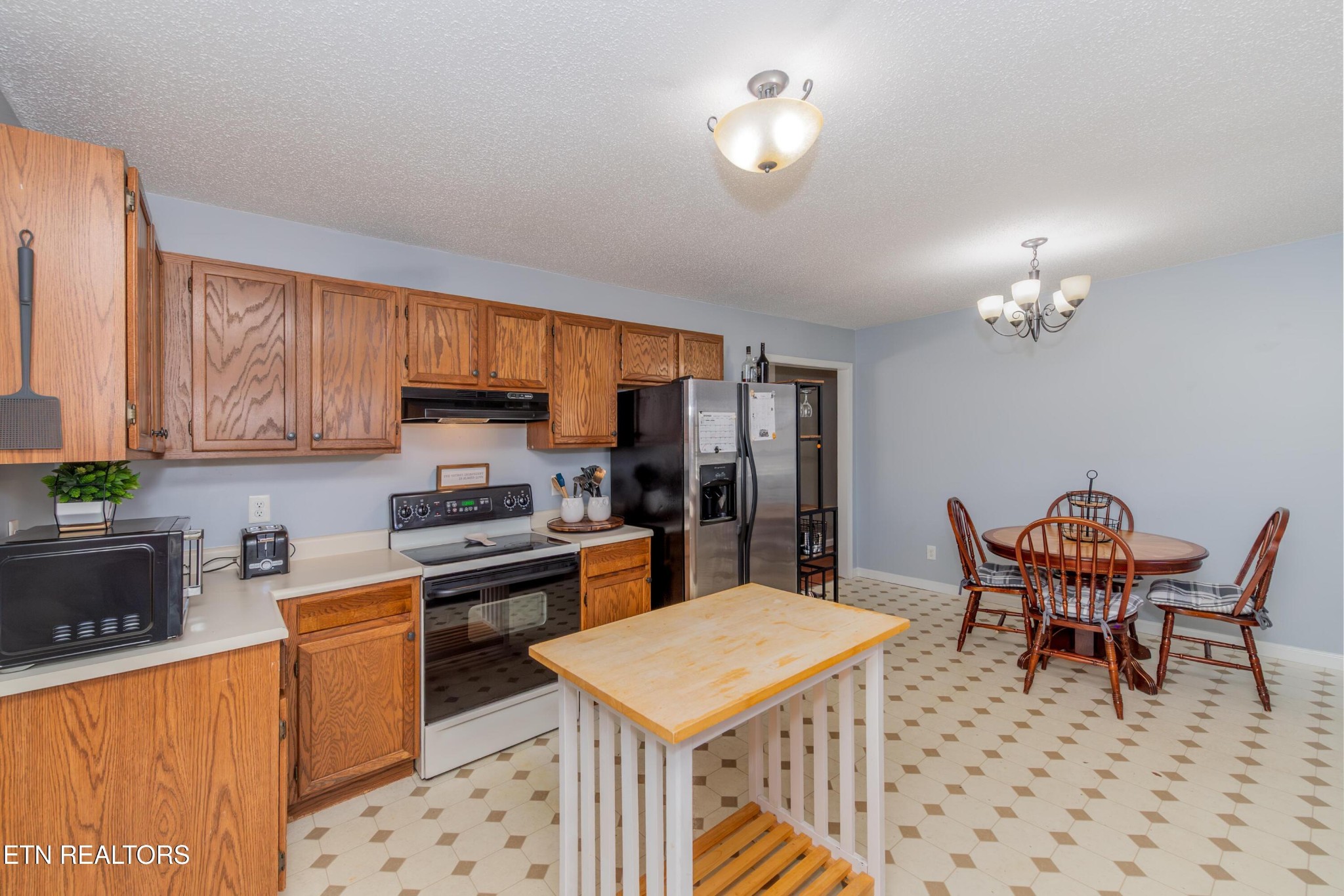 3919 Morganton Road Maryville, TN 37801 - Photo 15 of 29 a kitchen with stainless steel appliances granite countertop a stove a refrigerator a sink dishwasher a dining table and chairs with wooden floor