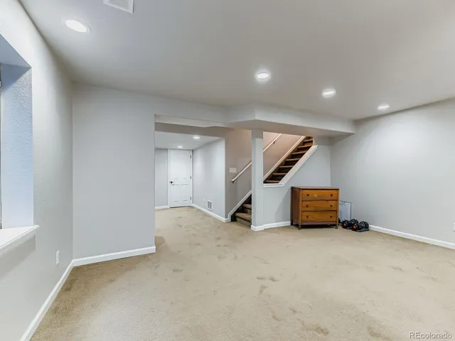 an empty room with stairs and wooden floor