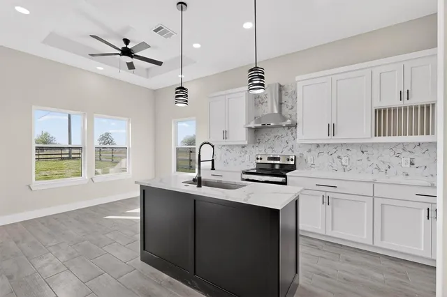 a kitchen with stainless steel appliances granite countertop a sink a stove cabinets and a window