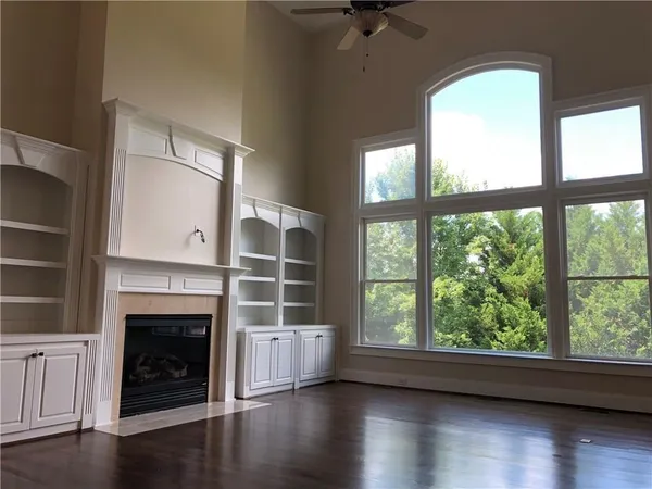 a view of a livingroom with a fireplace wooden floor and windows
