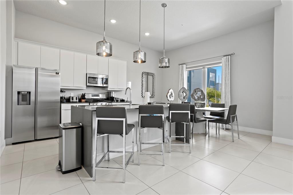 7770 Sandy Ridge Drive, Unit 207 Reunion, FL 34747 - Photo 10 of 61 a kitchen with stainless steel appliances kitchen island granite countertop a refrigerator a stove a sink a dining table and chairs