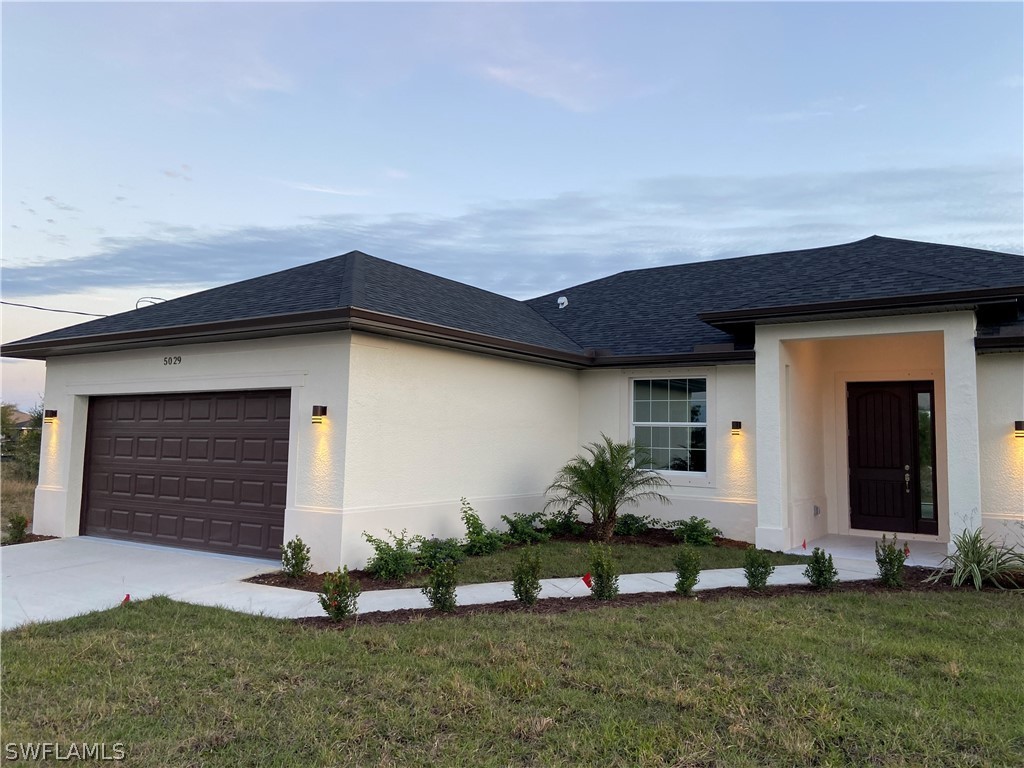 5029 Bristo Street Lehigh Acres, FL 33971 - Photo 3 of 14 a front view of a house with a yard and garage
