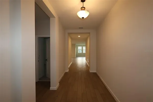 a view of a hallway with wooden floor and a bathroom