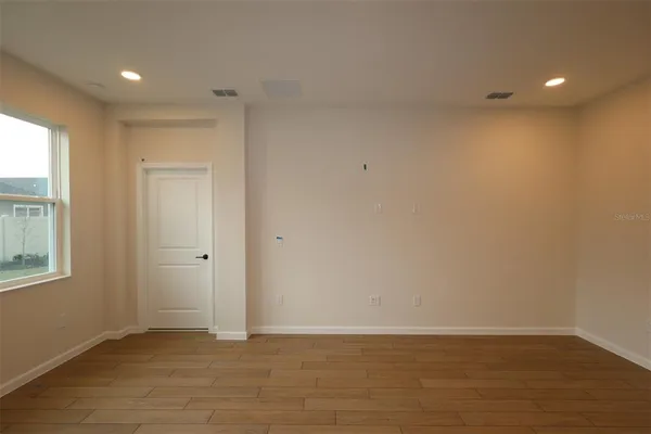 a view of an empty room with wooden floor and a window