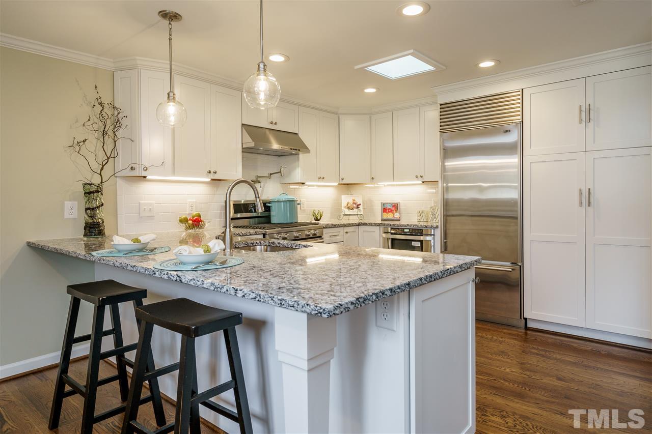 1707 Sutton Drive Raleigh, NC 27605 - Photo 8 of 29 a kitchen with kitchen island granite countertop a sink a center island and cabinets