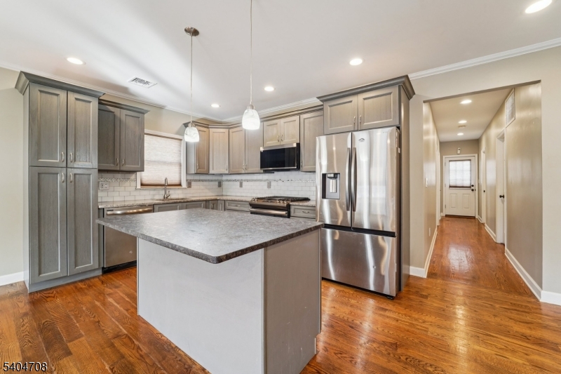 a kitchen with stainless steel appliances granite countertop a refrigerator a sink a stove a microwave and wooden floor