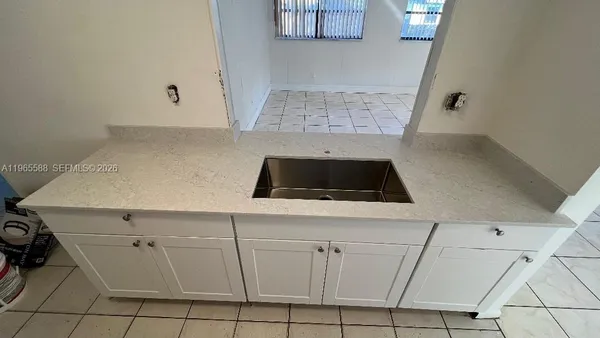 a kitchen with white cabinets and sink