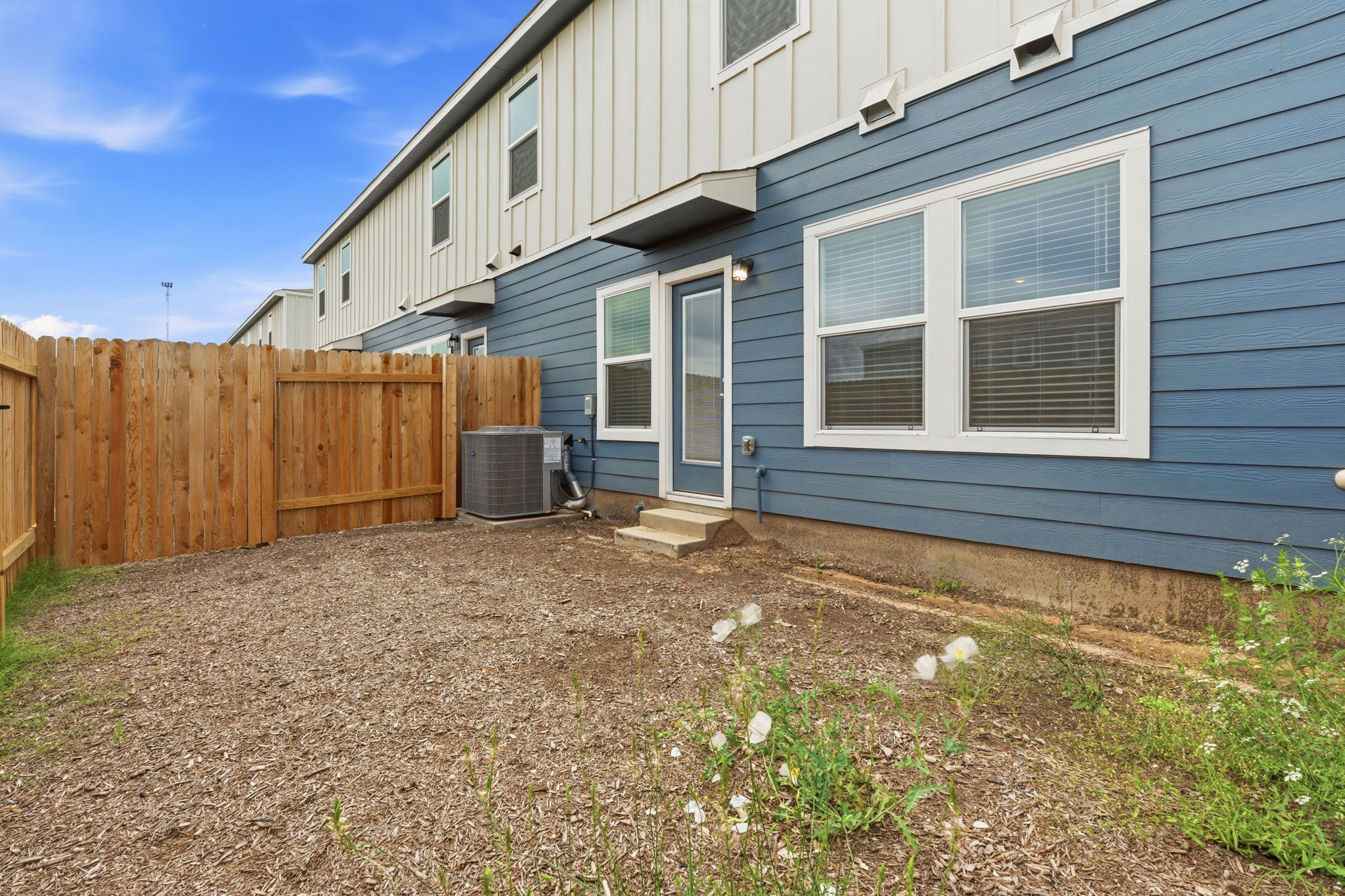164 Cinnabar Lane, Unit 3 Kyle, TX 78640 - Photo 20 of 20 Private outdoor space featuring a wood fence, a rear entry door, and two large windows