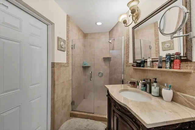 a bathroom with a granite countertop sink a mirror a vanity and a shower