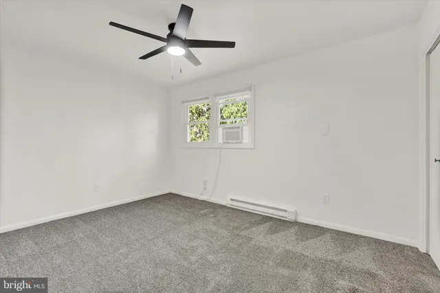 an empty room with a window and a fan