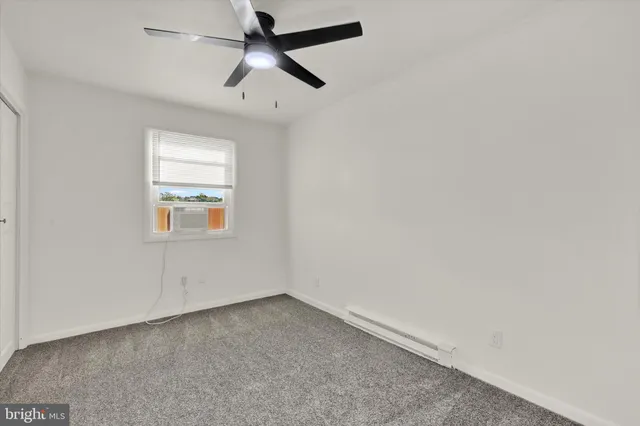 an empty room with a window and a fan