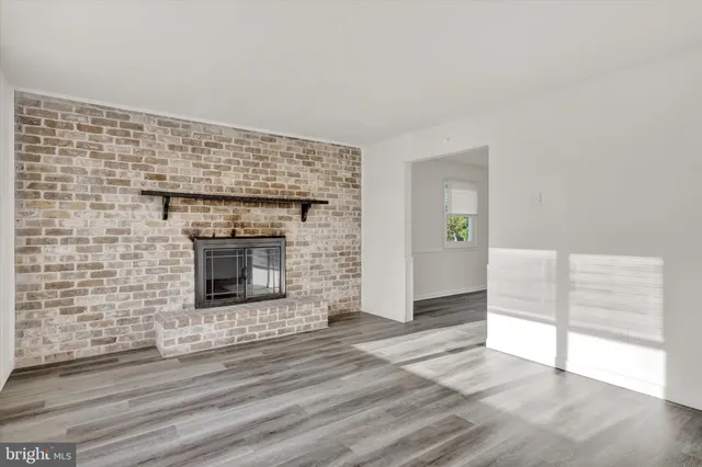 an empty room with wooden floor fireplace and windows